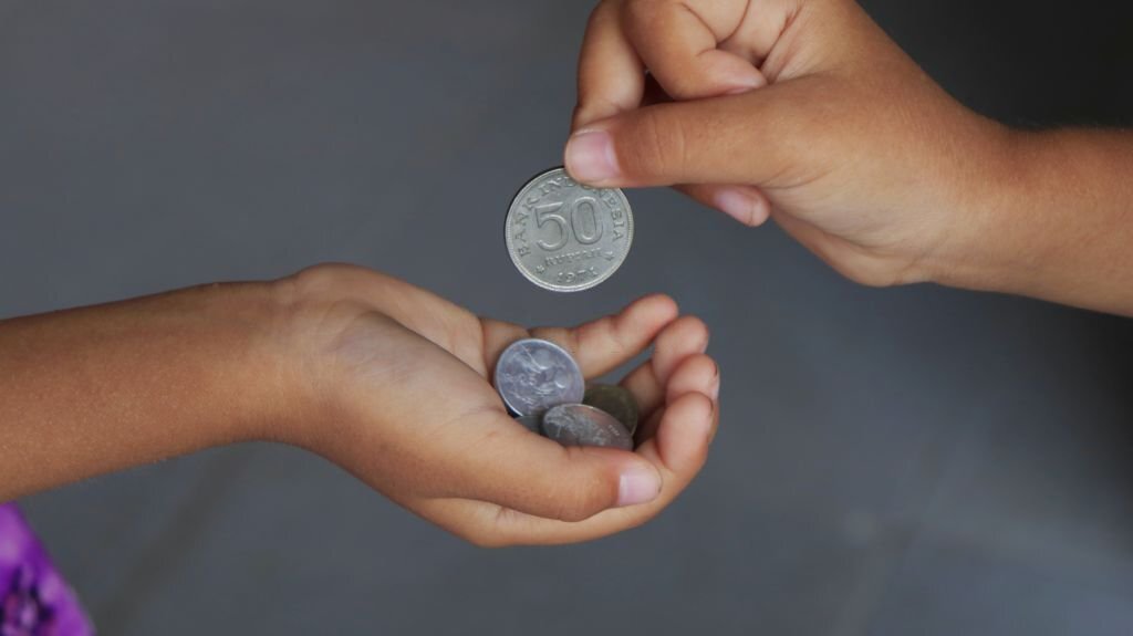 Hand giving coin to child as money saving concept in vintage color tone